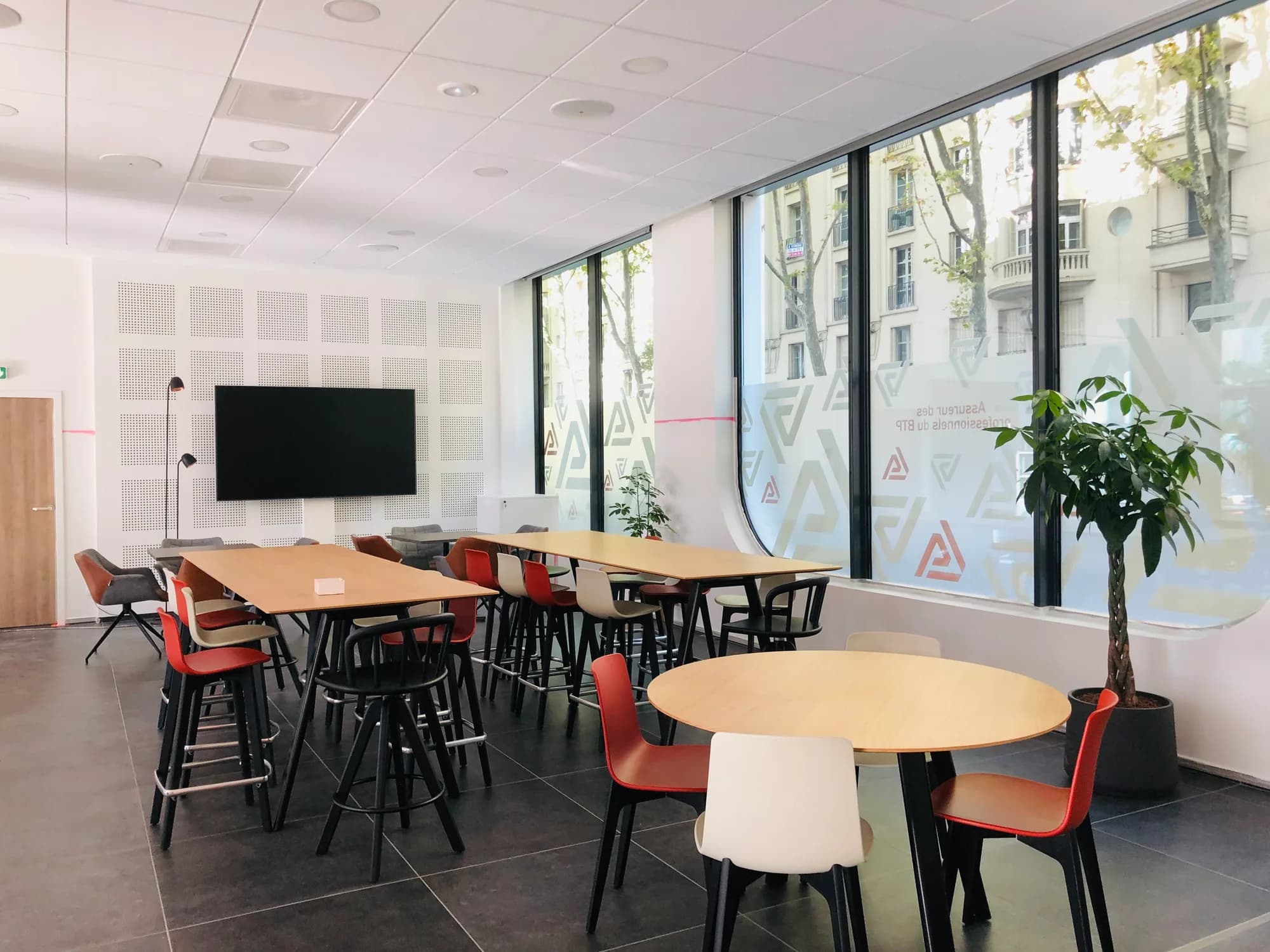 Espace de travail partagé avec de grandes baies vitrées, des tables et des assises
