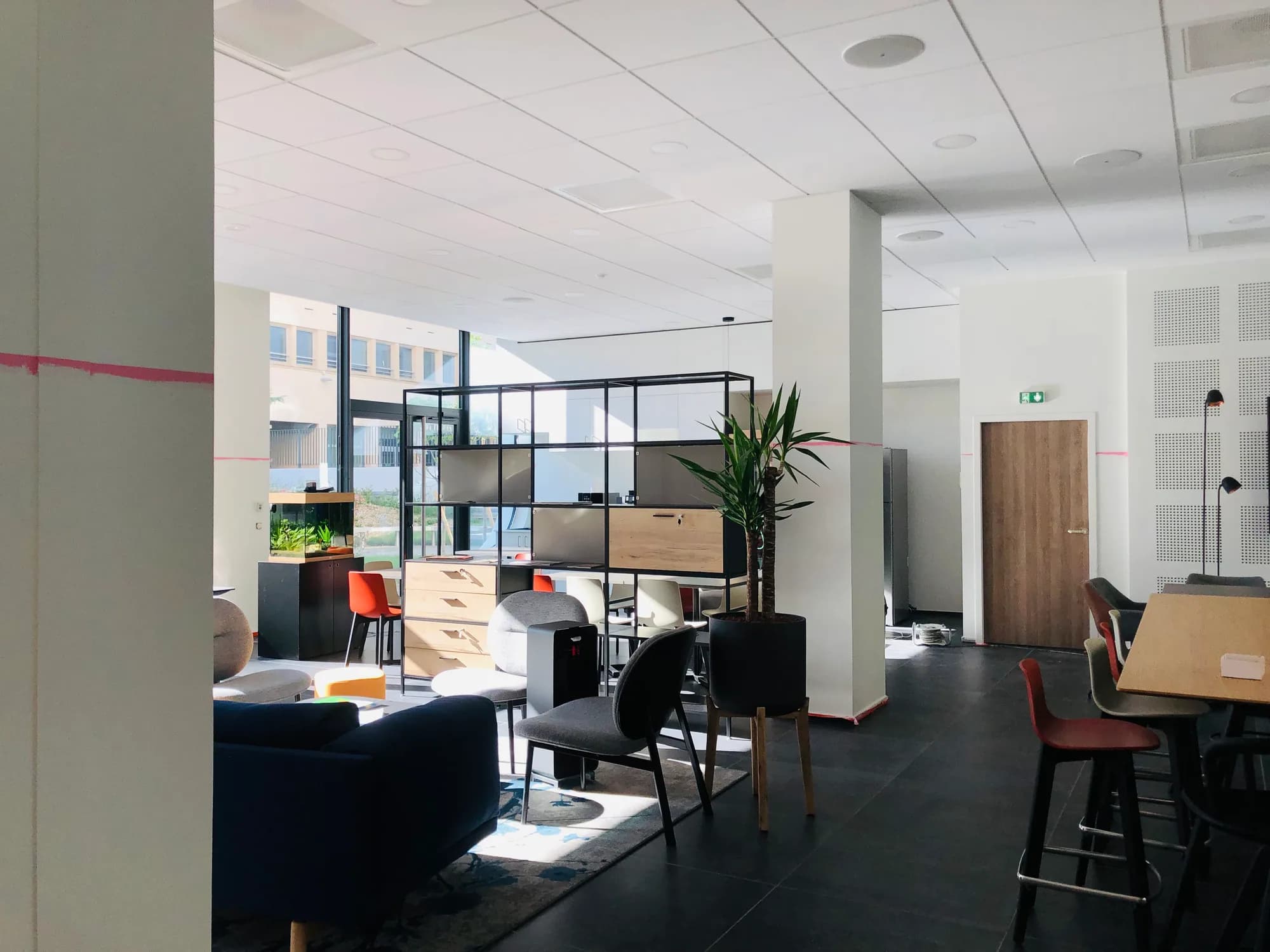 Espace commun de bureaux avec salon, tables et cloisons vitrées
