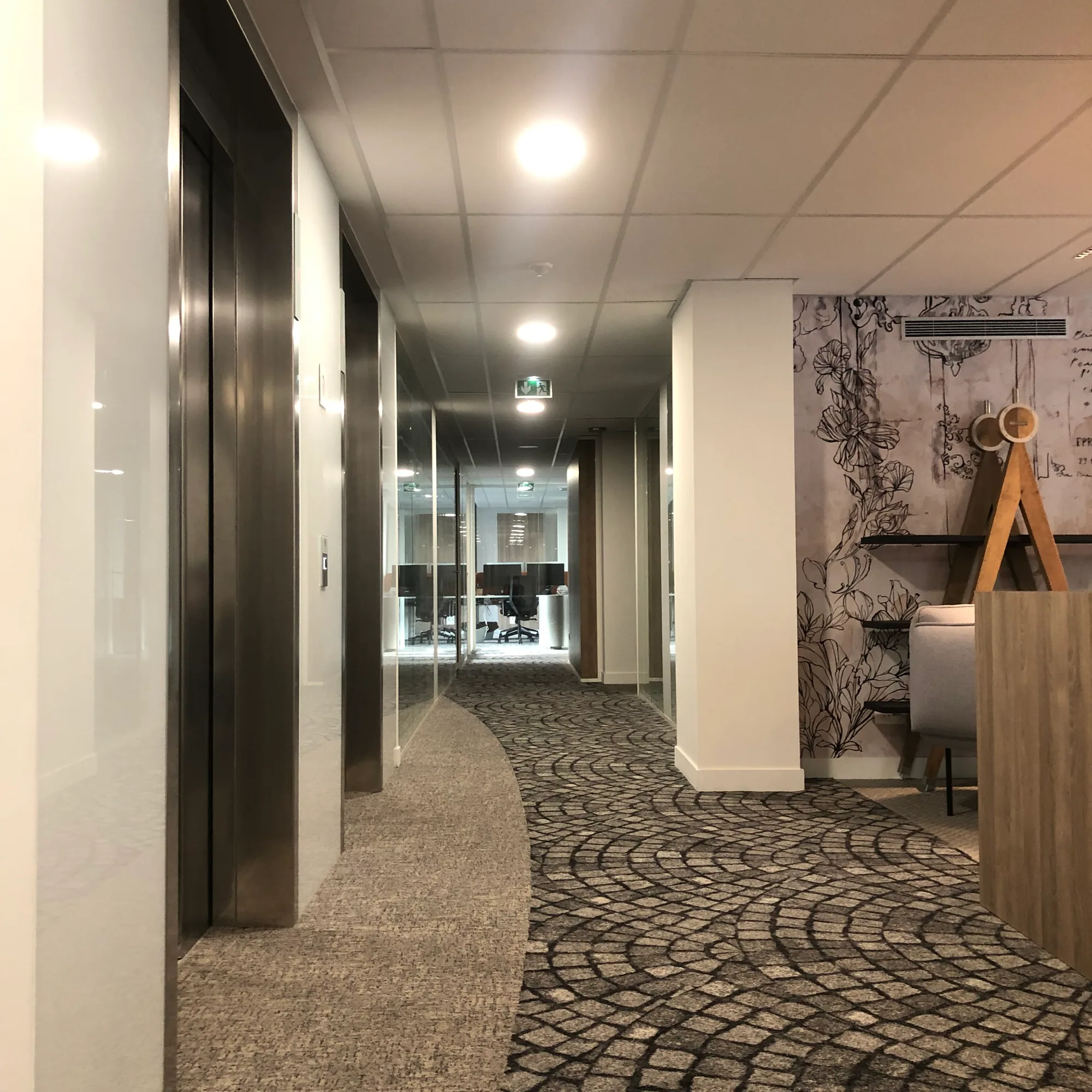 Couloir de bureaux avec moquette à motifs et portes vitrées