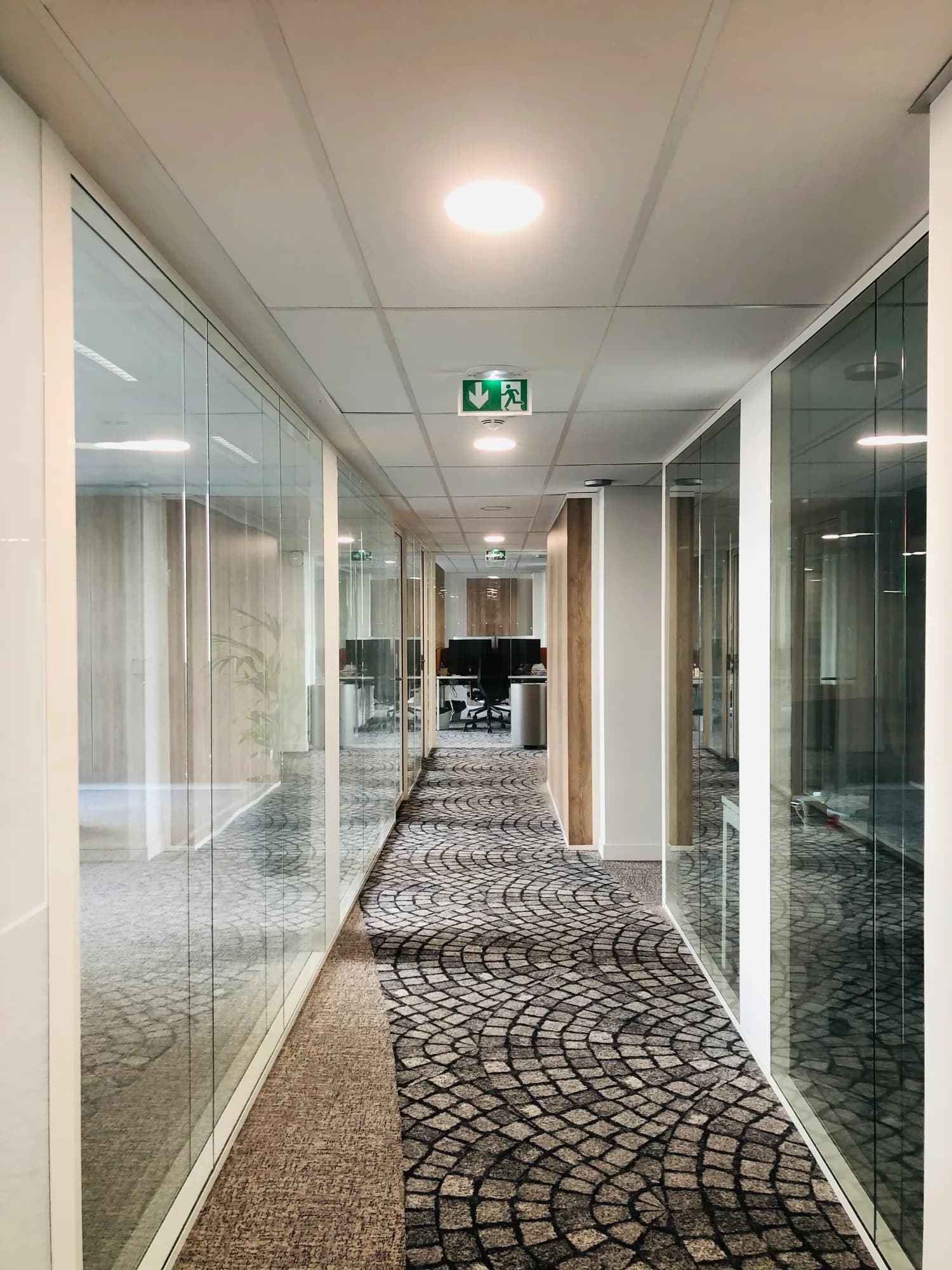 Couloir central desservant des bureaux séparés par des cloisons vitrées