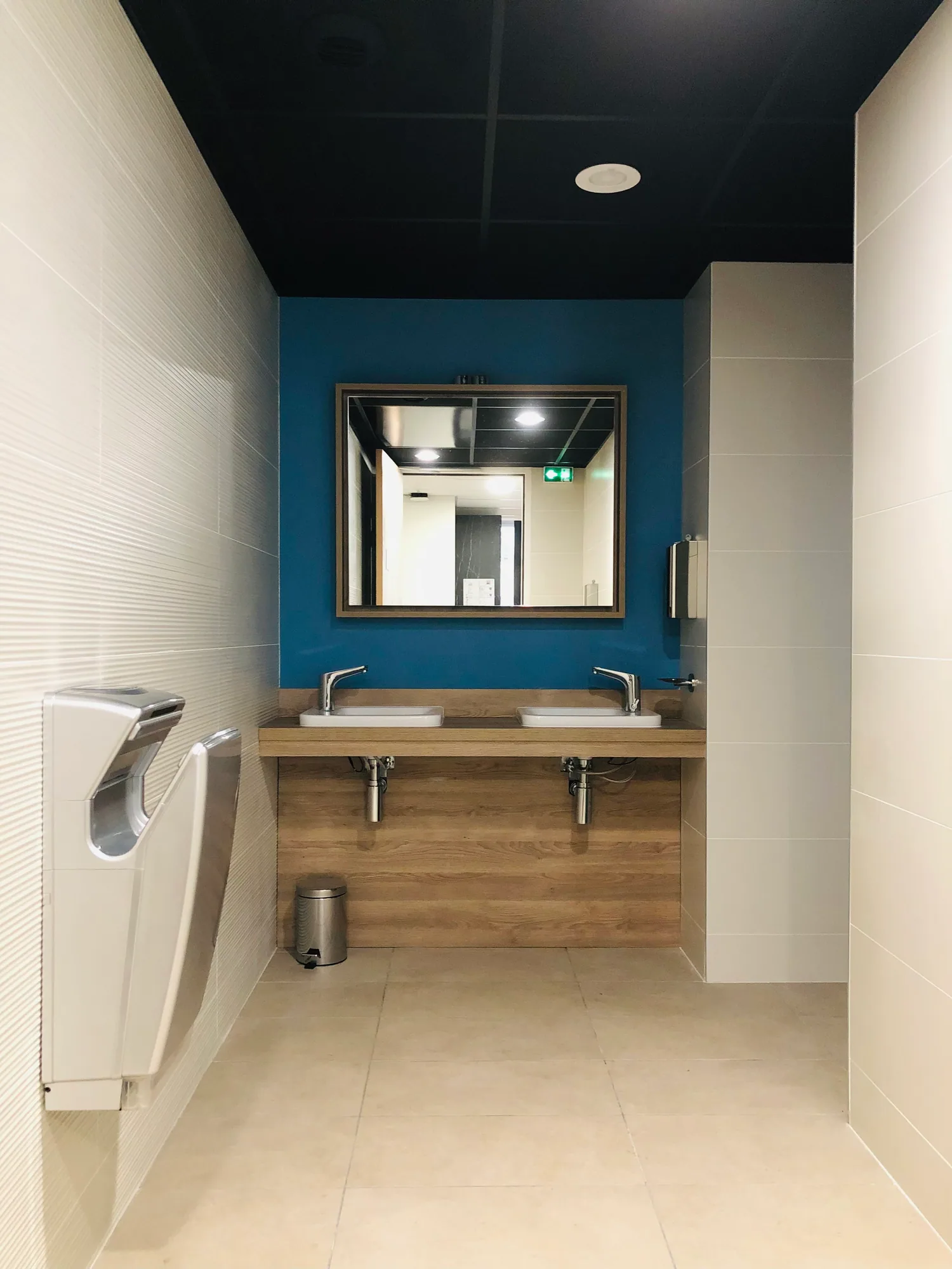 Sanitaires avec lavabos, murs clairs et mur du fond bleu