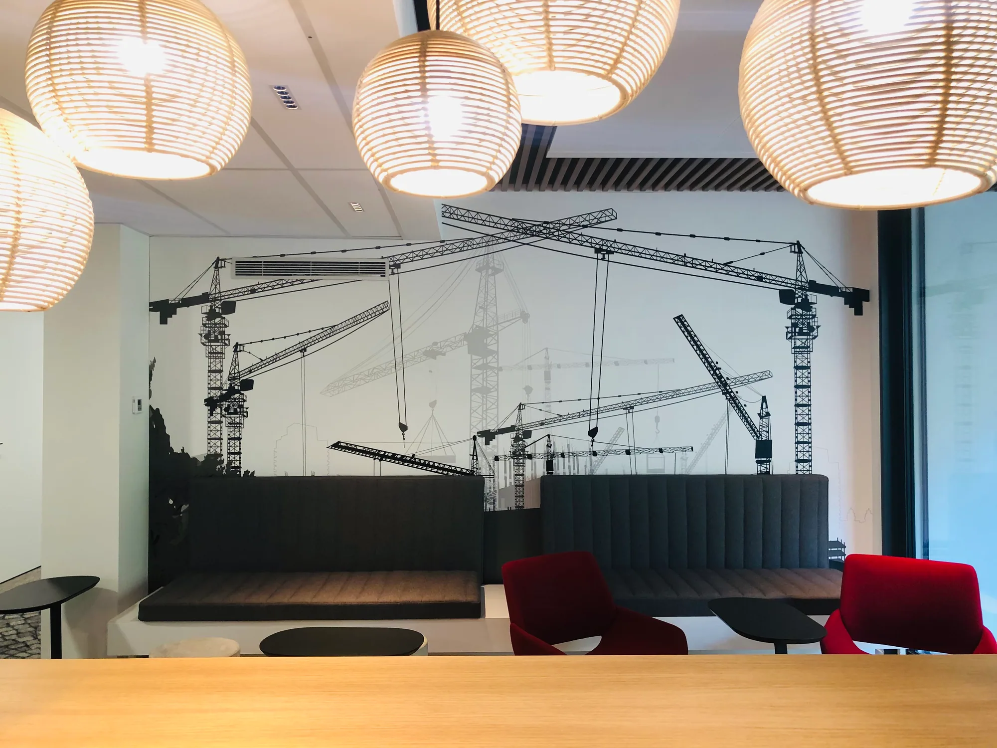 Salle de réunion avec banquette, table et décor mural représentant des grues