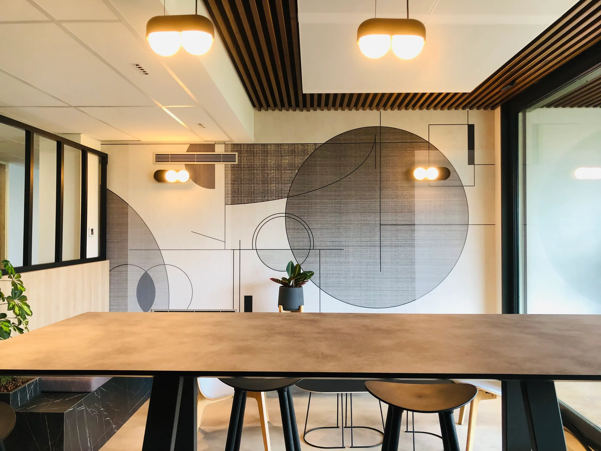 Salle de réunion avec grande table, suspensions et plafond à lames noires