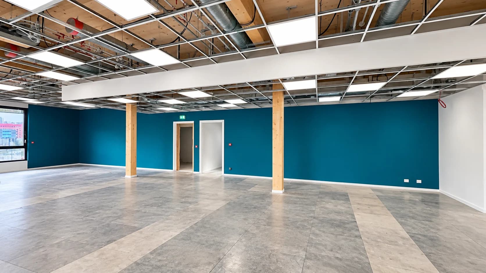Plateau de bureaux avec mur bleu, poteaux en bois et plafond technique apparent