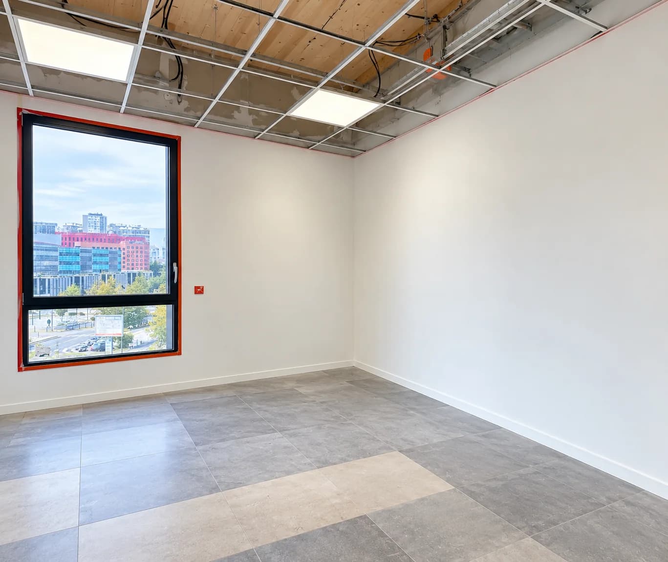 Espace intérieur avec fenêtre, murs blancs et plafond en cours d’aménagement
